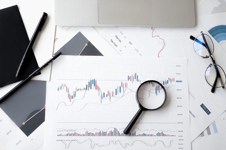 A magnifying glass over printed sales charts